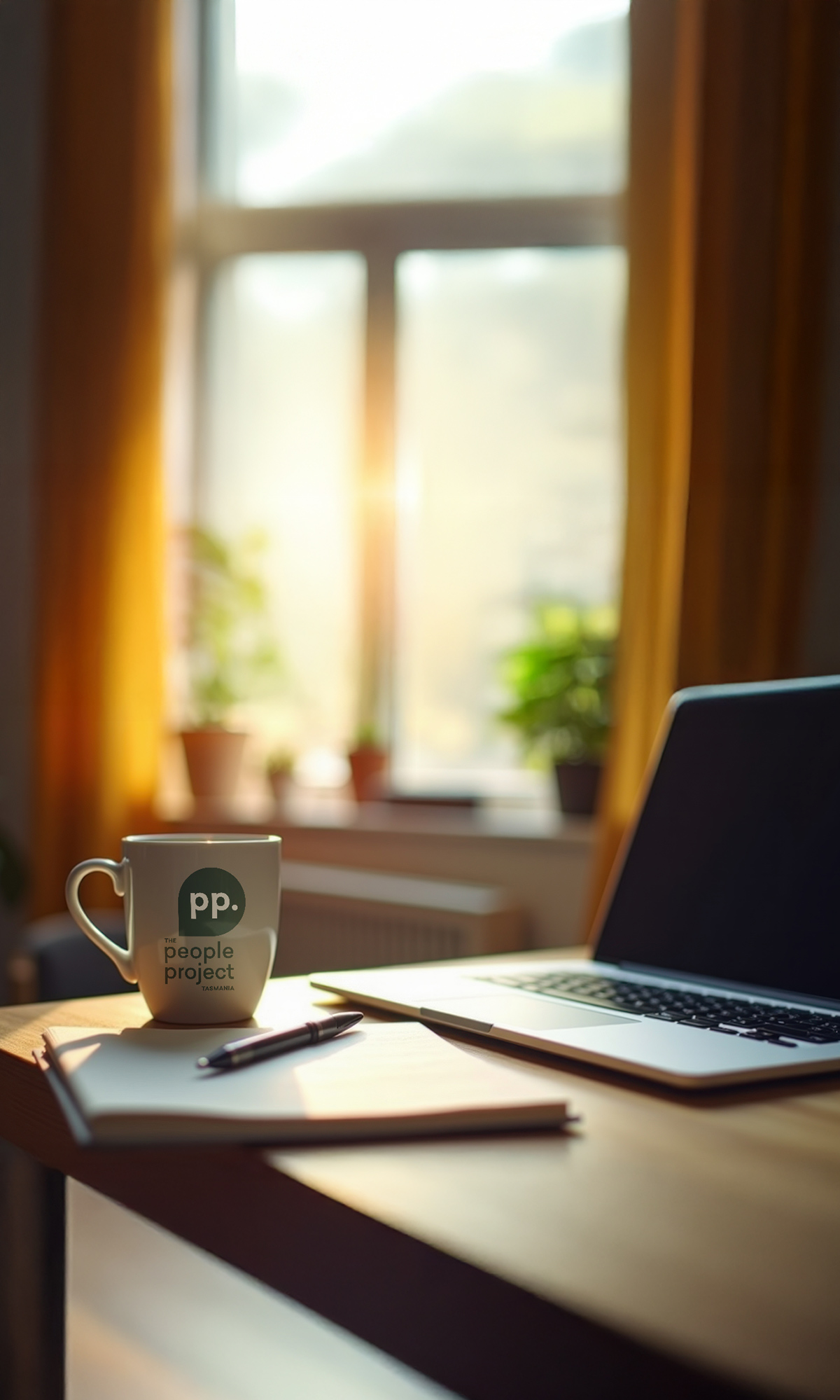 Laptop on a desk next to a The People Project Tasmania branded mug, representing website terms of use.